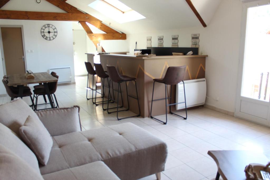 a living room with a couch and a bar at Superbe Appartement Circuit des 3 Chateaux in Folembray