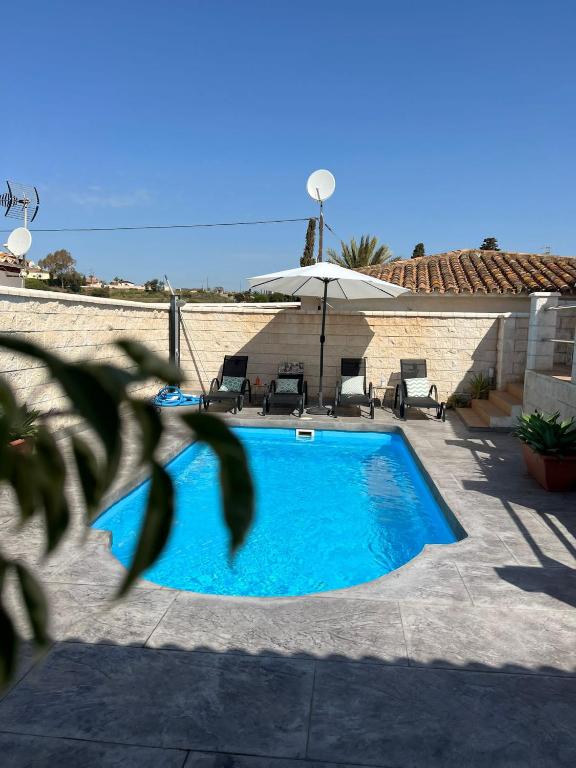 a blue swimming pool with chairs and an umbrella at MONTE AZUL in Málaga