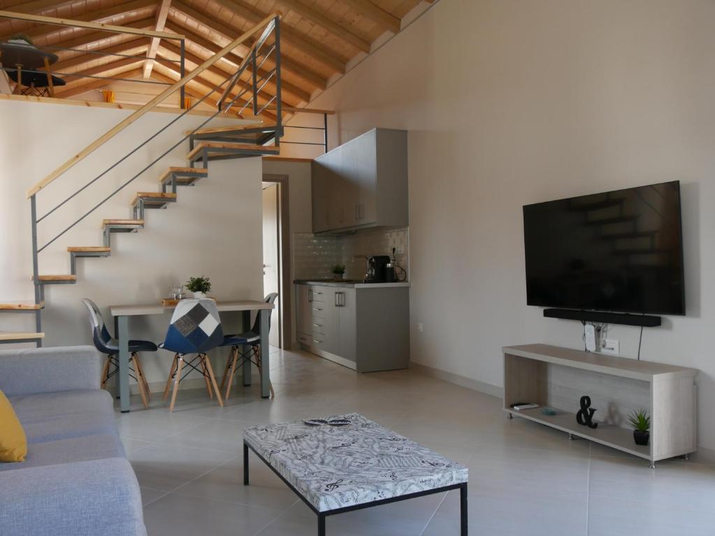 a living room with a couch and a tv and a staircase at TH Studio in Myrina