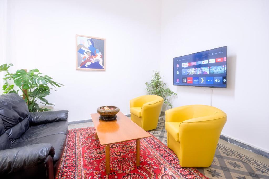 a living room with two yellow chairs and a tv at Right House via Sulis 23 - Best Neighborhood in Town in Cagliari