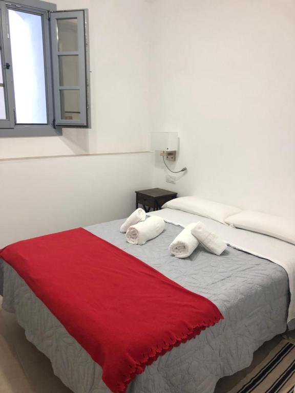 a bedroom with a large bed with a red blanket at Apartamentos Casa la Costanilla in Vejer de la Frontera