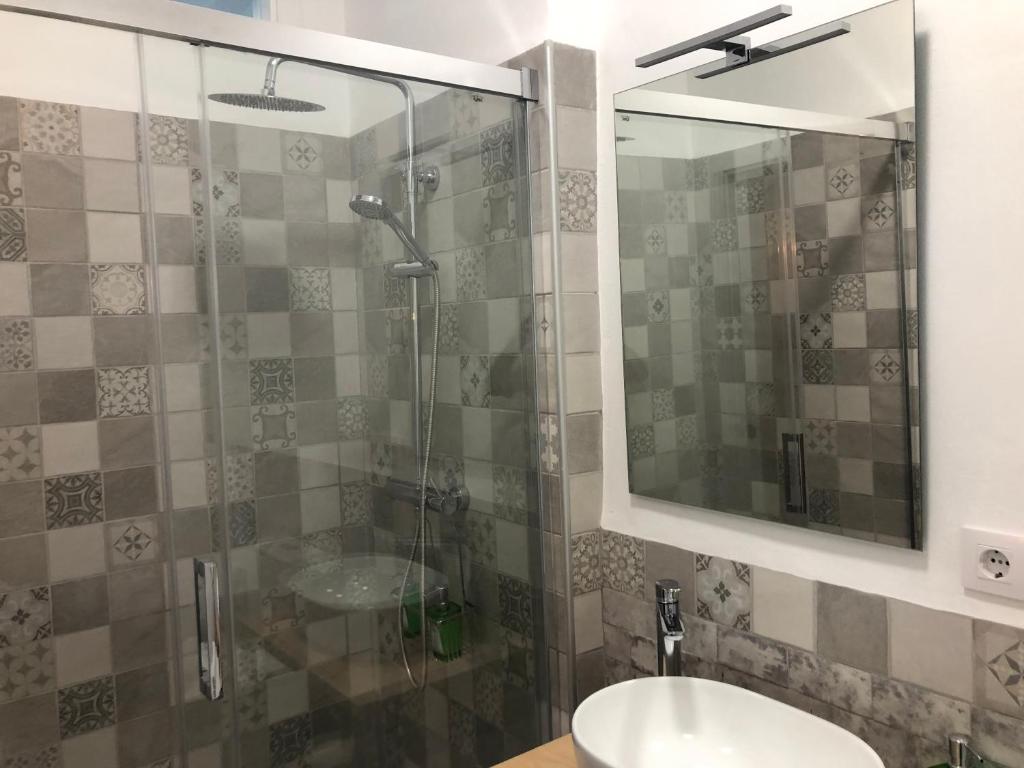 a bathroom with a sink and a shower with a mirror at Apartamentos Casa la Costanilla in Vejer de la Frontera