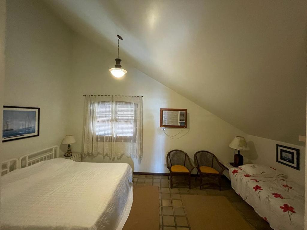 um quarto com uma cama e duas cadeiras em Guaeca Villa em São Sebastião