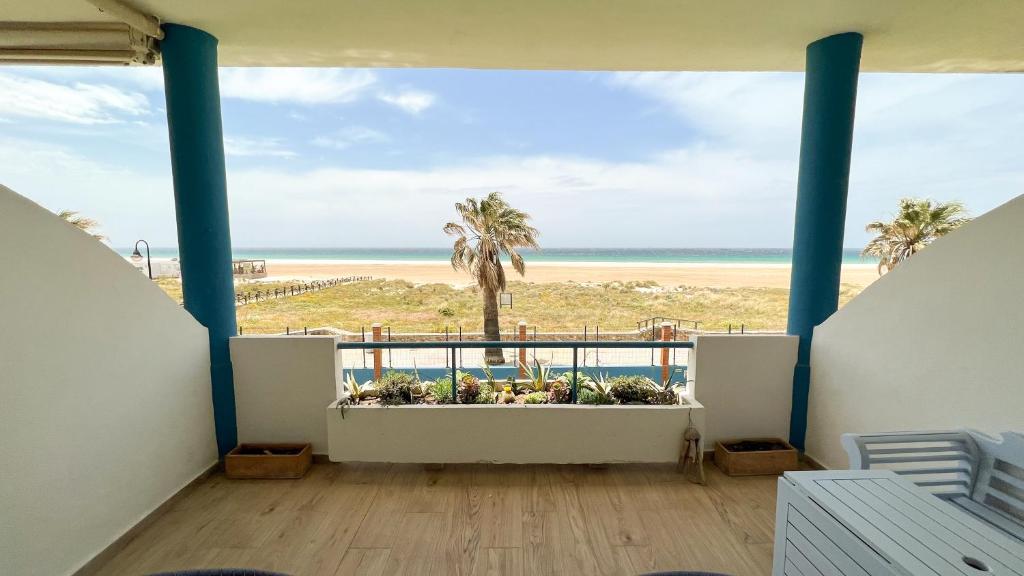 a balcony with a view of the beach and palm trees at Tarifa Cozy House - Beachfront, Stylish Deco in Tarifa