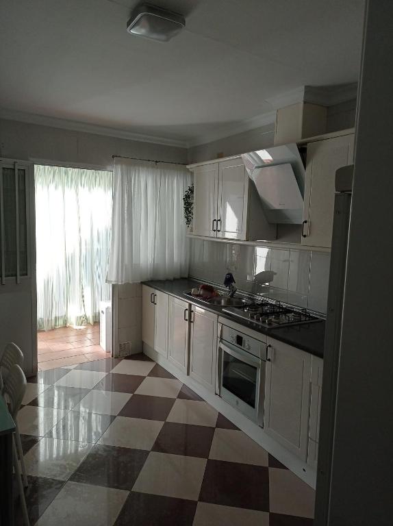 eine Küche mit weißen Schränken und einem karierten Boden in der Unterkunft Casa en casco urbano de Riogordo in Ríogordo