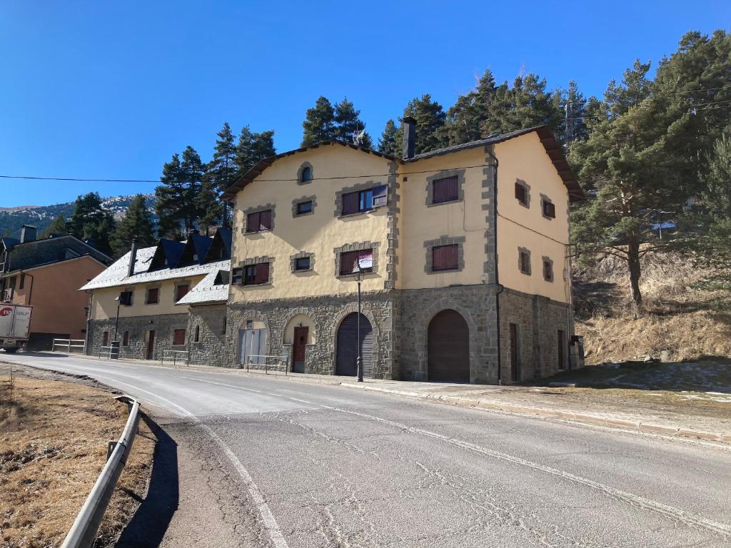 un gran edificio de piedra al lado de una carretera en Apartamento LA MOLINA, en Alp