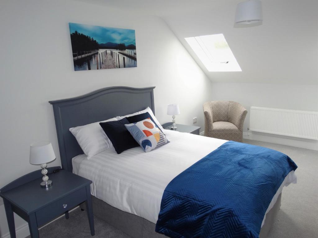 a bedroom with a bed with a blue blanket and a chair at Lir Lodge in Castlepollard