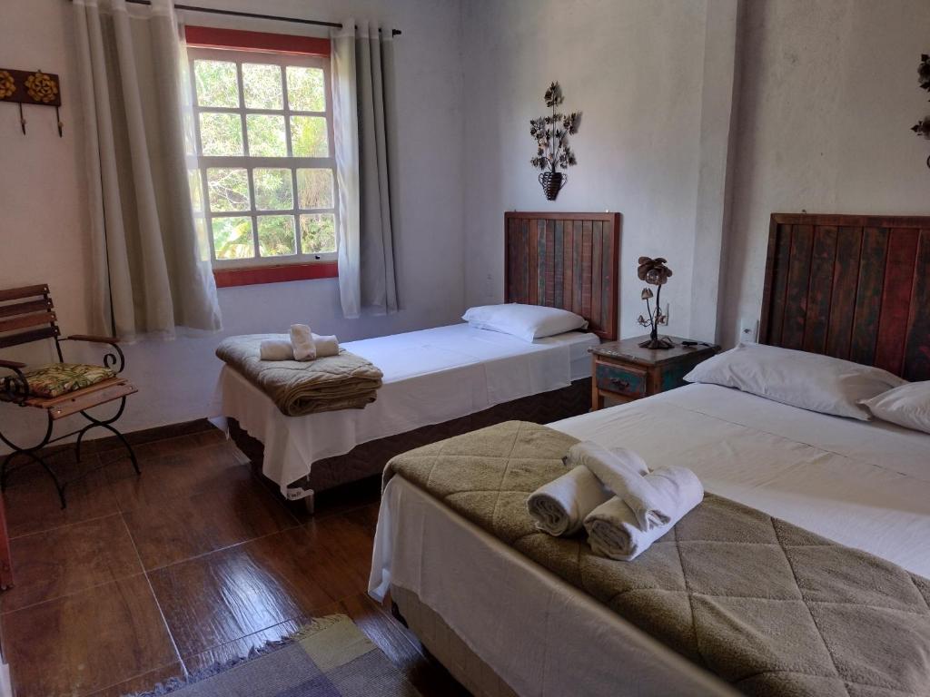 1 dormitorio con 2 camas y ventana en Hospedaria Estrada Real, en Tiradentes