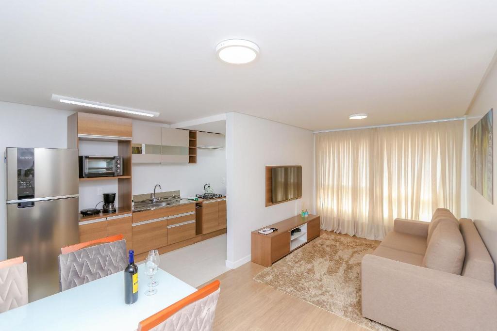 uma cozinha e sala de estar com uma mesa e um sofá em Wynn Residences - 609 em Caxias do Sul