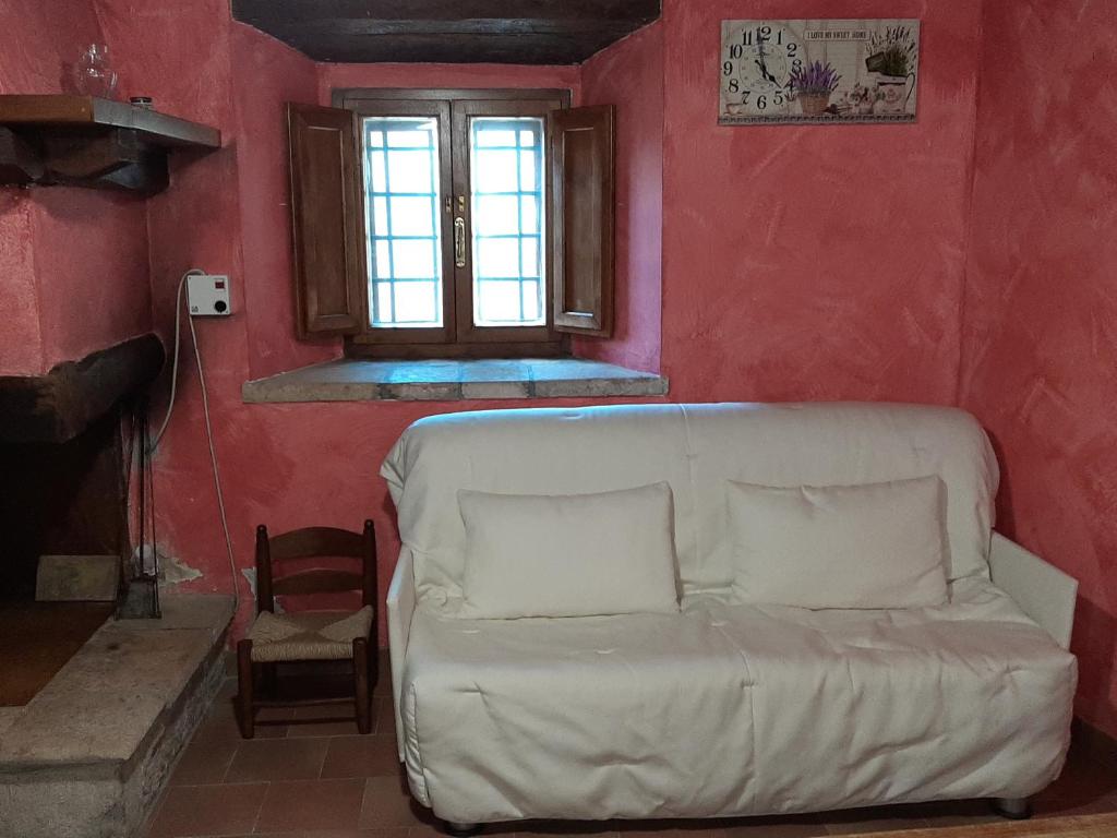 salon z białą kanapą w czerwonej ścianie w obiekcie Casa Piccolo Borgo w mieście Campello sul Clitunno