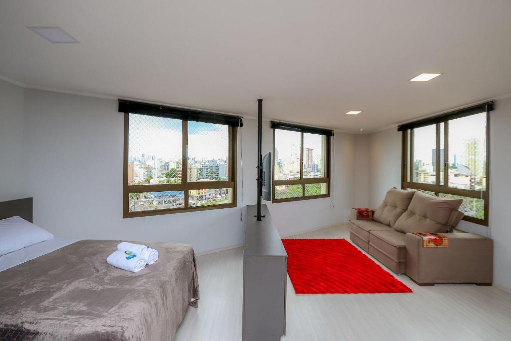 a bedroom with a bed and a couch and windows at Paseo Del Molino - 703 in Caxias do Sul