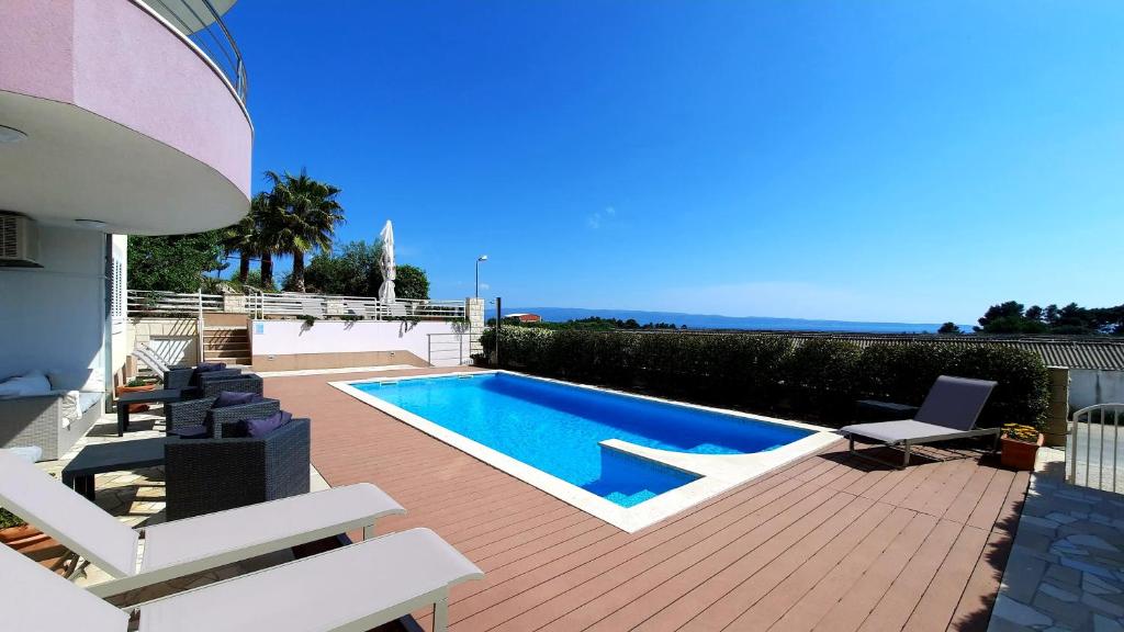 a backyard with a swimming pool and a deck with chairs at SEA VIEW- spacious apartment with shared pool in Split