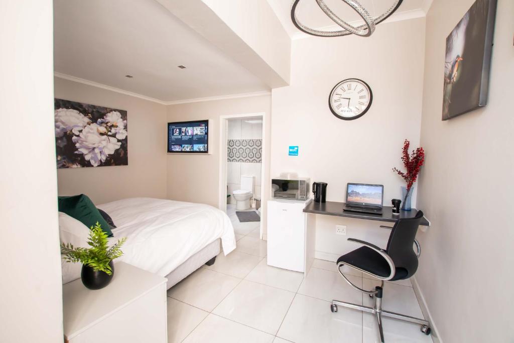 1 dormitorio con cama, escritorio y reloj en Prestigious Apartments en Fourways