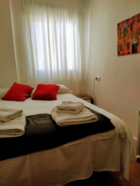 ein Schlafzimmer mit einem Bett mit roten Kissen und einem Fenster in der Unterkunft Victoria home in Málaga