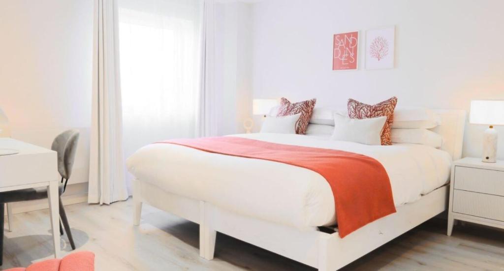a white bedroom with a large bed with a red blanket at St Moritz Hotel and Cowshed Spa in Polzeath