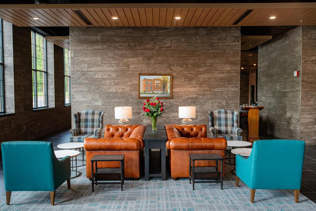 eine Lobby mit Ledermöbeln, einem Tisch und Stühlen in der Unterkunft The Schoolhouse Hotel in White Sulphur Springs