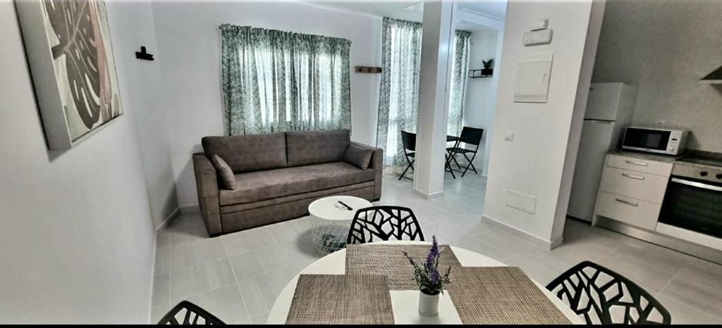 uma sala de estar com um sofá, uma mesa e cadeiras em Cardón Jandía 1B em Morro del Jable