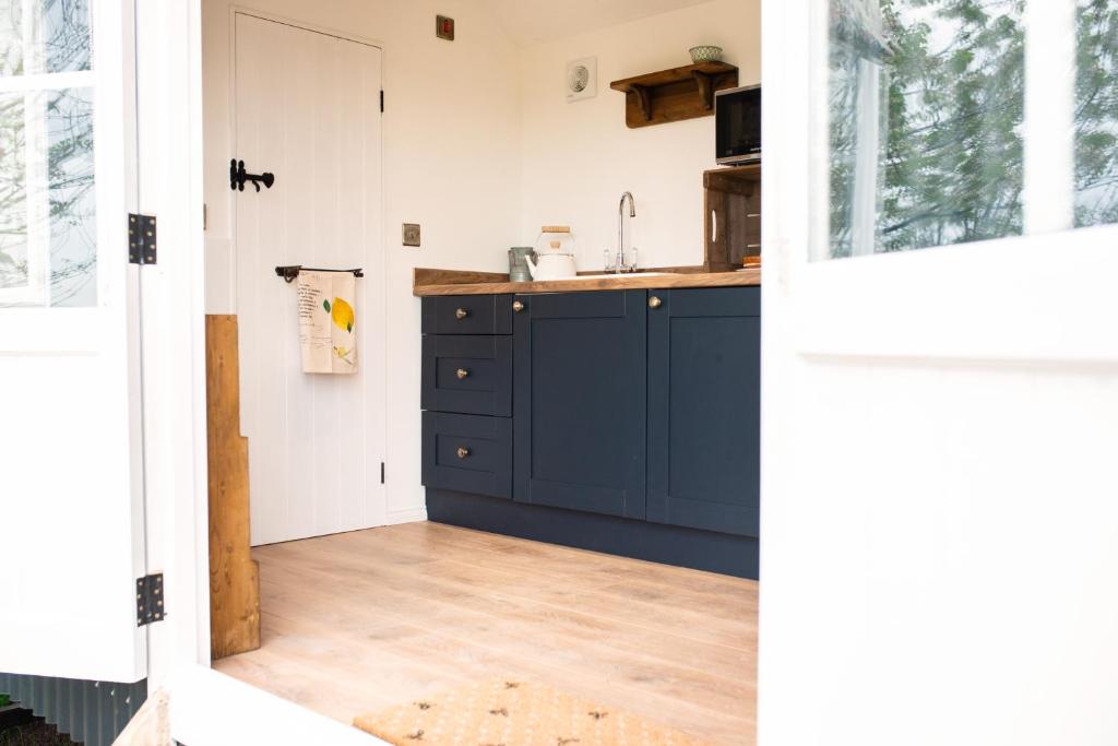 a kitchen with blue cabinets and a wooden floor at Drift View Shepherds Hut in Melton Mowbray
