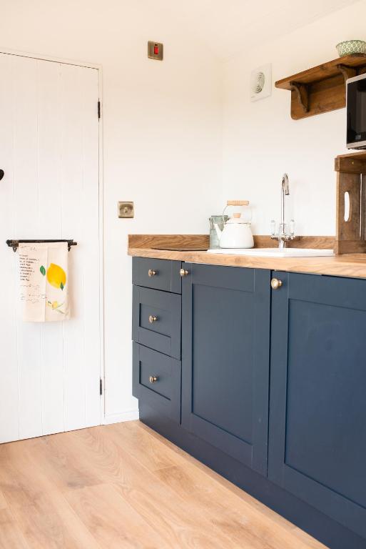 a kitchen with blue cabinets and a counter top at Drift View Shepherds Hut in Melton Mowbray