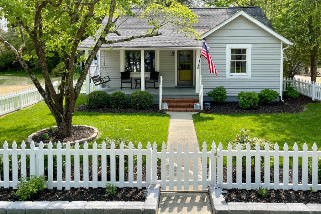 a white picket fence in front of a house at Urbanna Cottage with Private Yard and Water Views in West Irvington