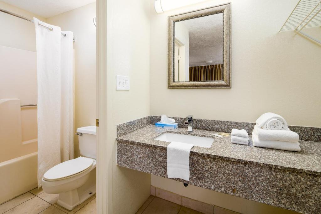 a bathroom with a sink and a toilet and a mirror at Americana Inn a Travelodge by Wyndham in Pigeon Forge
