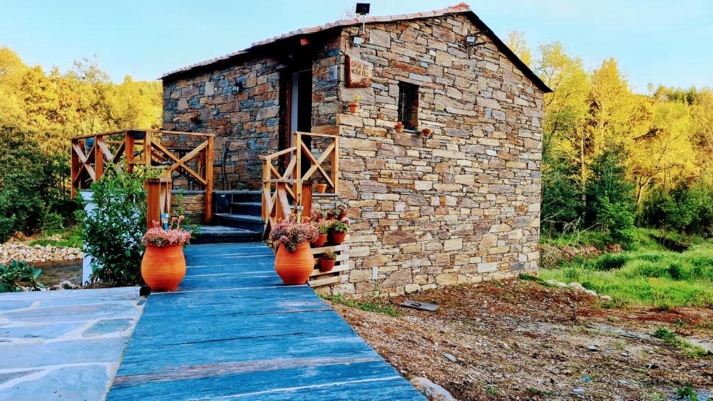 a stone building with three vases on a wooden walkway at Casa do Moleiro in Lousã