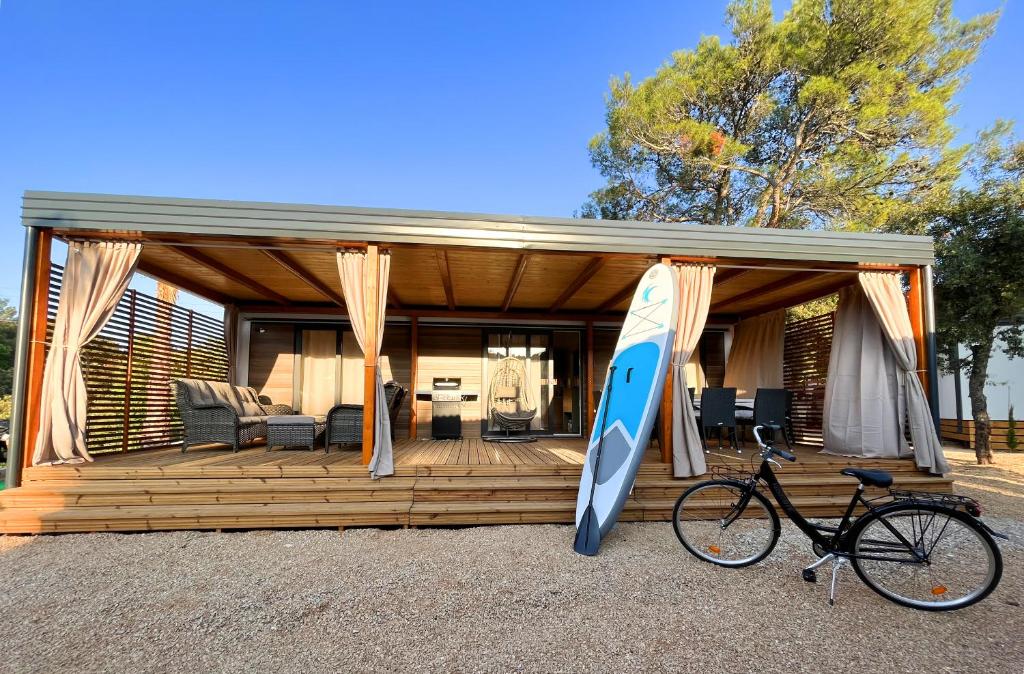 a house with a surfboard and a bike parked in front of it at Mobile Home Karlo in Biograd na Moru