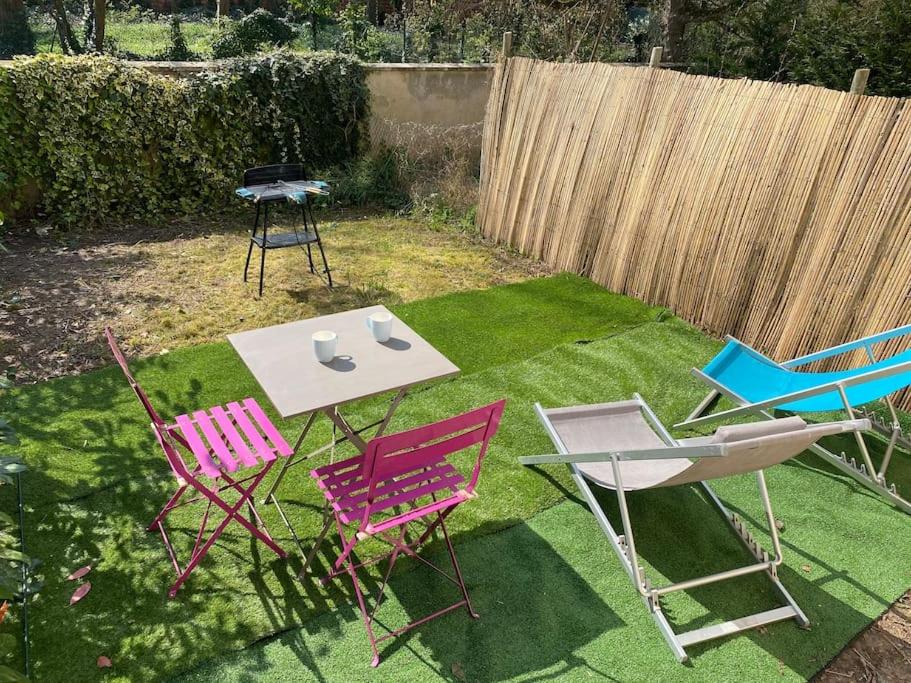 een groep stoelen en een tafel in een tuin bij Appartement Cosy avec jardin privatif et garage in Fontainebleau