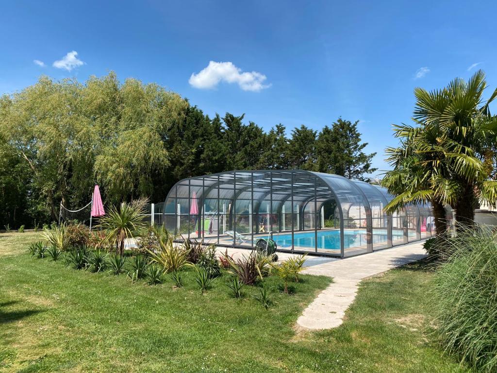 une maison en verre avec une piscine dans un jardin dans l'établissement Chambre d'hôtes La Belgerie, à Saint-Michel-en-lʼHerm