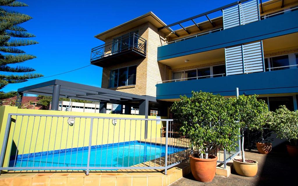 uma casa com piscina em frente a um edifício em Caribbean Motel em Coffs Harbour