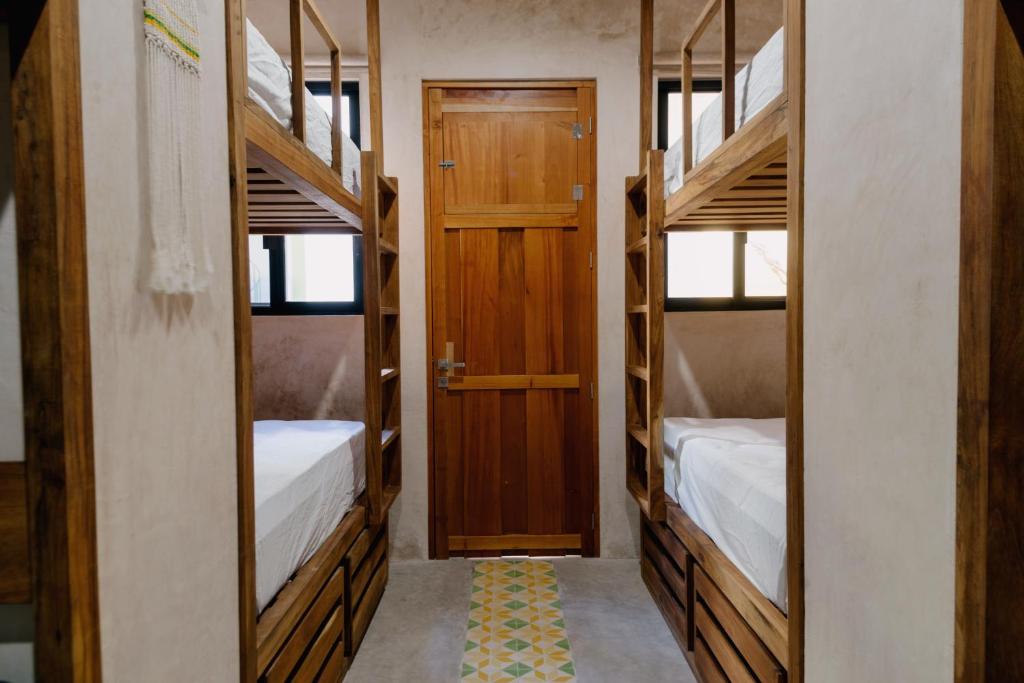 メリダにあるHostik Hostalの二段ベッド2台とドアが備わる客室です。