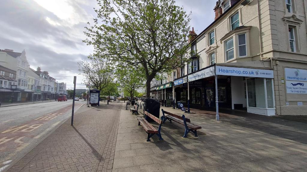 a sidewalk with benches on a city street at St Hilary Central Apartments in Llandudno