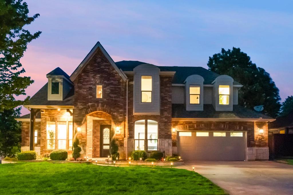 a house with a garage at dusk at Pool house with hot tub and cinema in Corinth