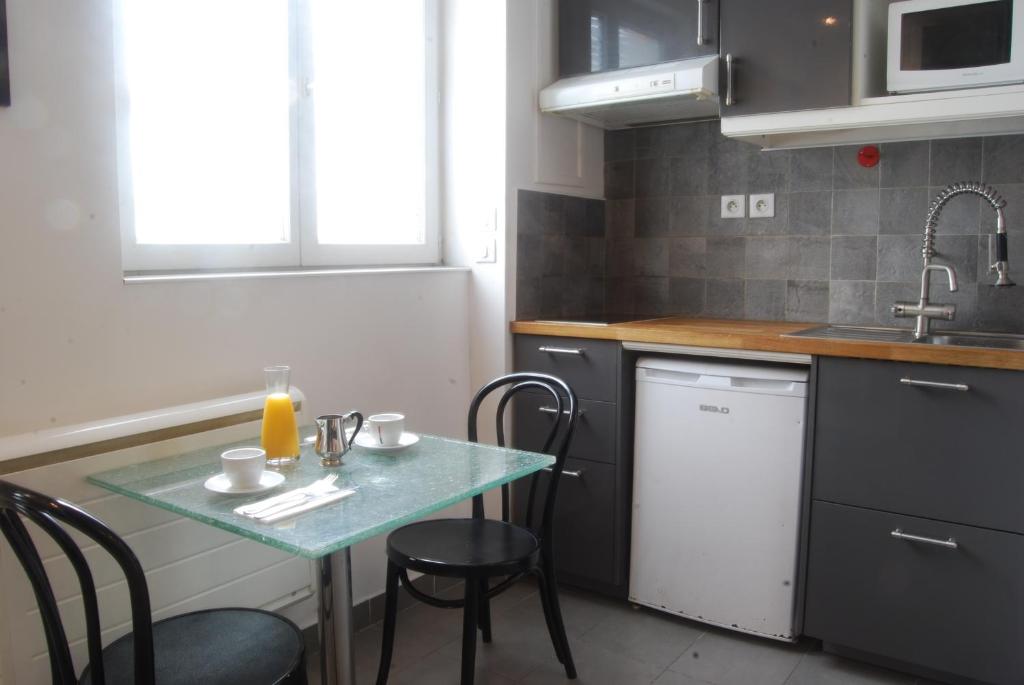 a small kitchen with a table with chairs and a sink at Appart-Hôtel Le Djurdjura Suresnes-Nanterre-La defense in Nanterre