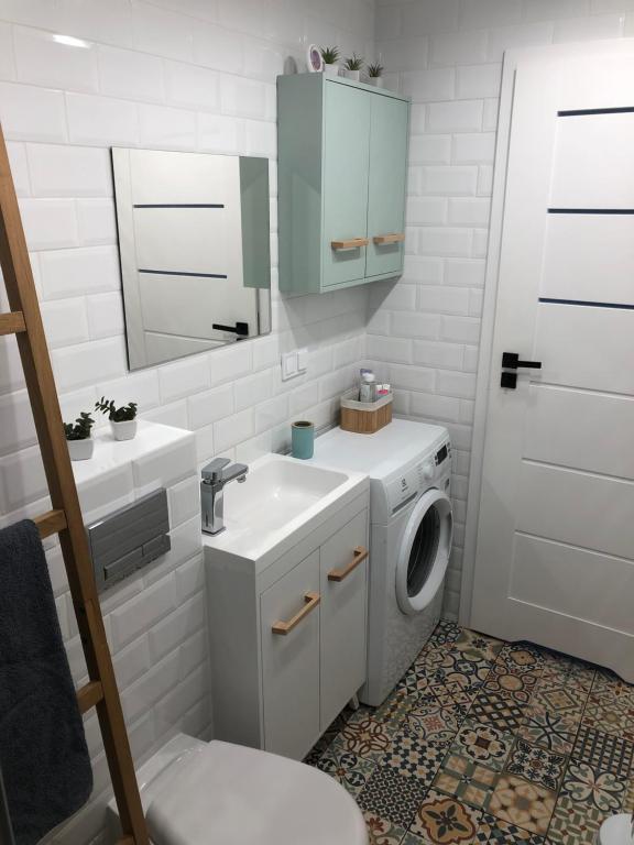 a bathroom with a sink and a washing machine at Apartament Mia in Malbork