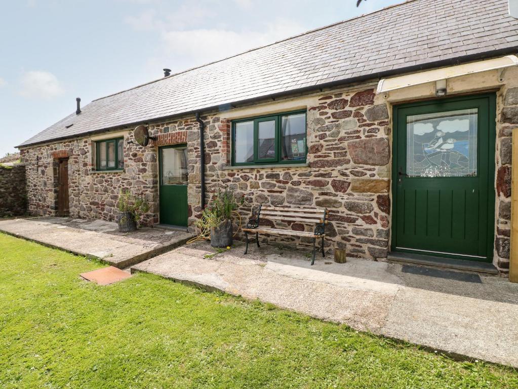 uma casa de pedra com uma porta verde e um banco em The Long Barn em Haverfordwest