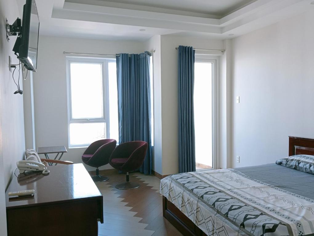 1 Schlafzimmer mit einem Bett, einem Schreibtisch und 2 Fenstern in der Unterkunft Anh Truc House - Near Front Beach in Vũng Tàu