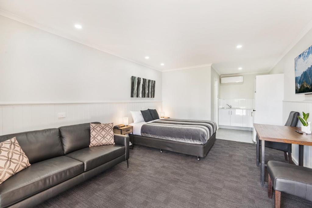 een woonkamer met een bank en een bed bij Allara Motor Lodge in Bendigo
