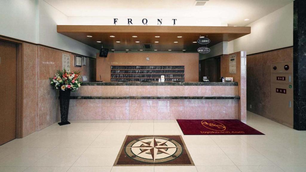 a front counter in a lobby with a flower arrangement at Toyoko Inn Kitakyushu Airport in Kitakyushu