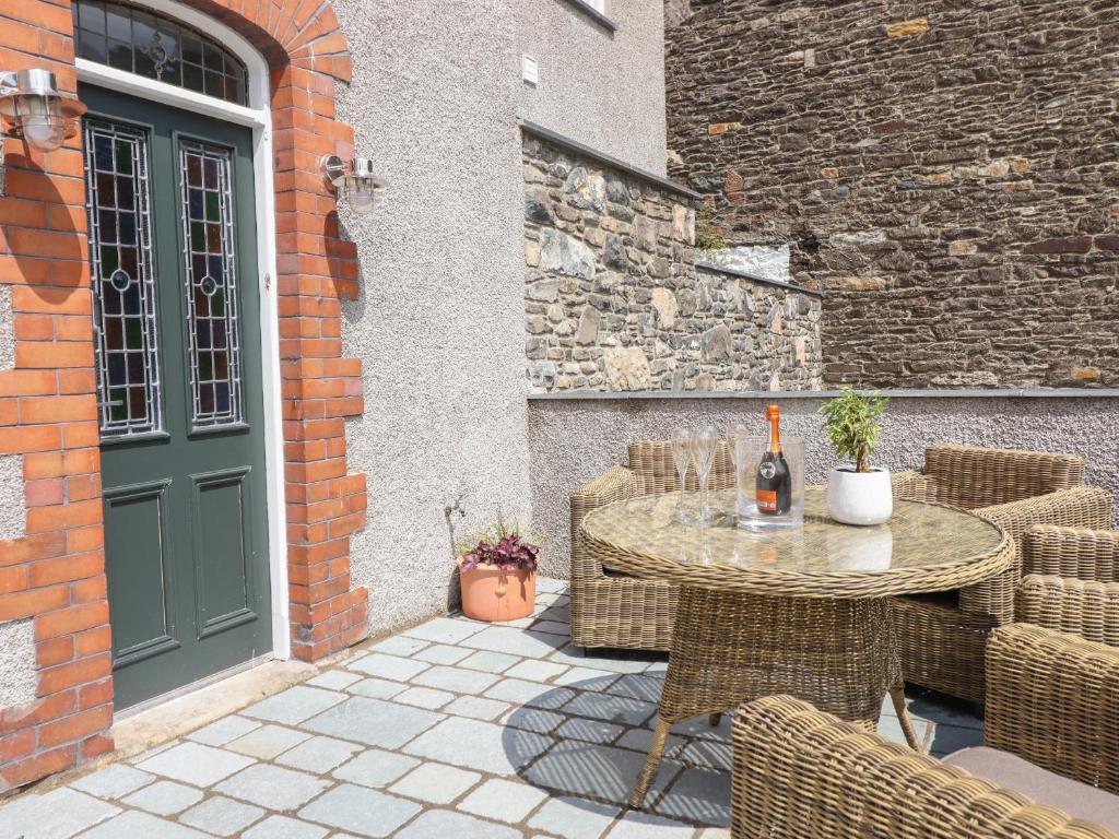 een patio met een tafel en stoelen en een groene deur bij 2 Llewelyn Street in Conwy