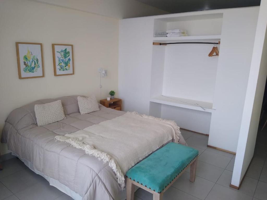a bedroom with a large bed with a blue stool at Departamento Paseo de los Poetas Premium in Salta