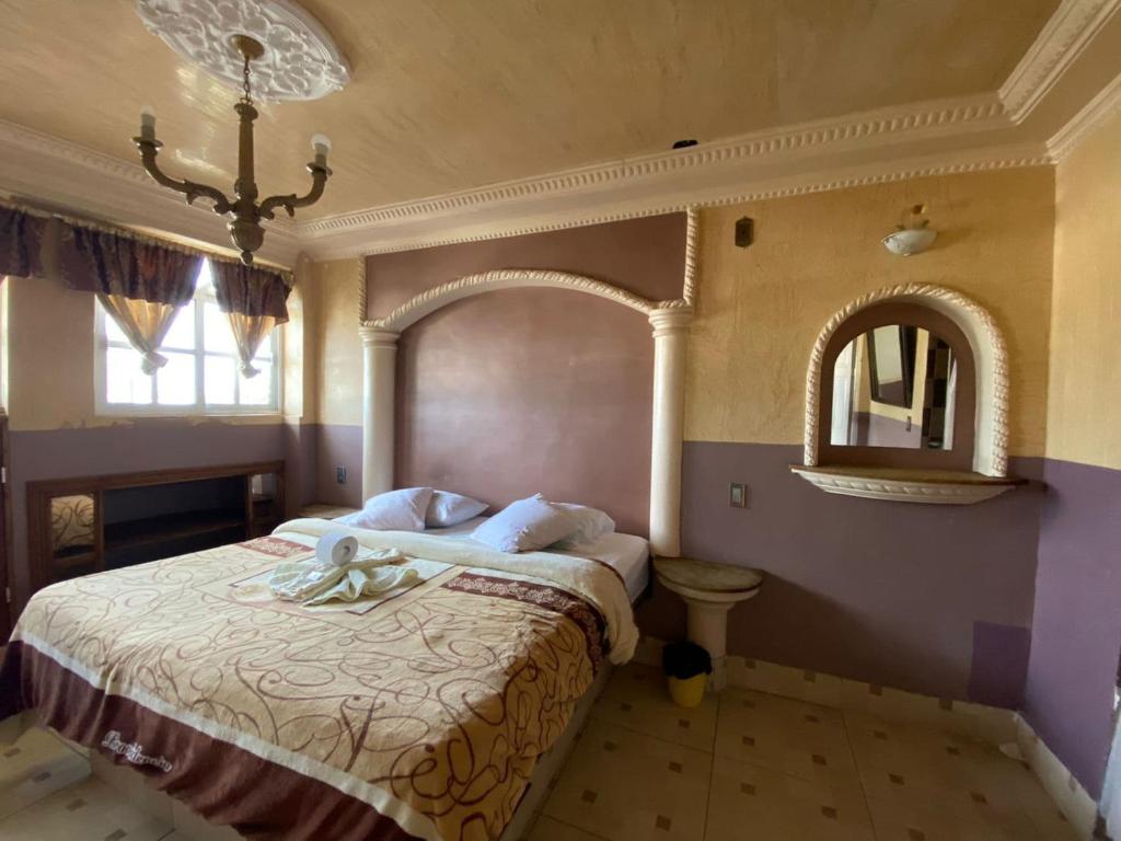 een slaapkamer met een groot bed en een spiegel bij Hotel Plaza in San Martín Texmelucan de Labastida
