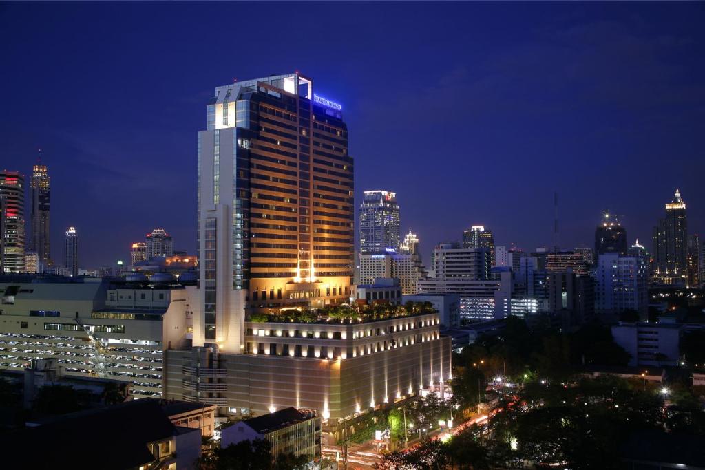 un bâtiment éclairé dans une ville la nuit dans l'établissement Pathumwan Princess Hotel - SHA Extra Plus Certified, à Bangkok