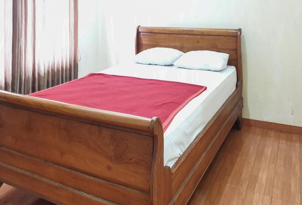 a wooden bed with two pillows on top of it at Hotel Mataram Cipanas Syariah Mitra RedDoorz in Pasakon 1