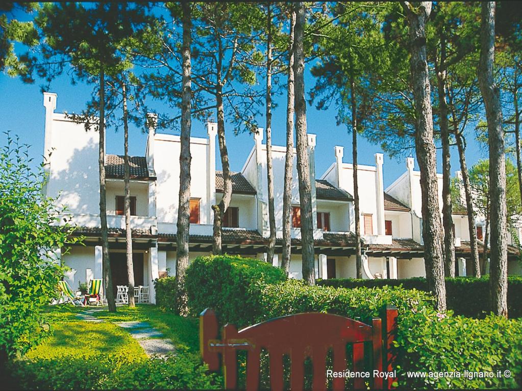 een groot wit huis met bomen ervoor bij Villa a Lignano Pineta in Lignano Sabbiadoro