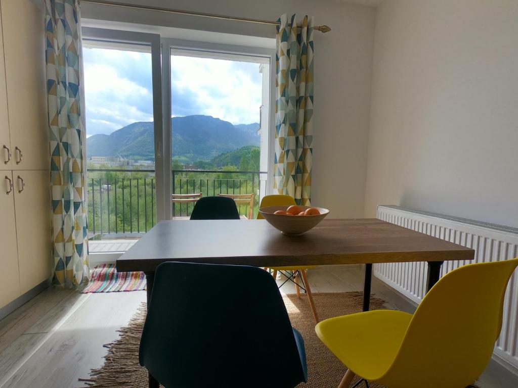 une salle à manger avec une table, des chaises et une grande fenêtre dans l'établissement Panoramic Residence, à Zărneşti