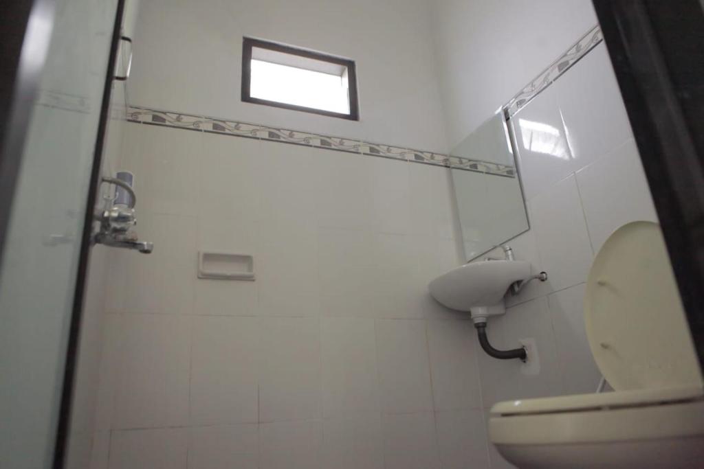 uma casa de banho branca com um WC e uma janela em Villa petit Tour em Batu