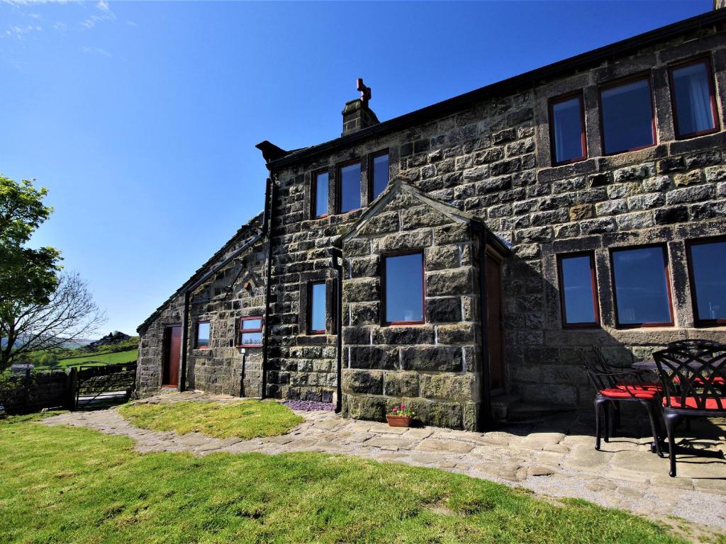 una vecchia casa in pietra con una panchina rossa davanti di Rake Hey Farm a Todmorden