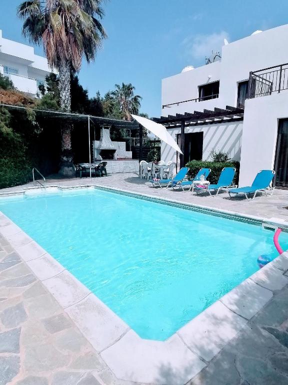 a swimming pool in a resort with chairs and a building at Spacious 3 bedroom villa private pool in Paphos