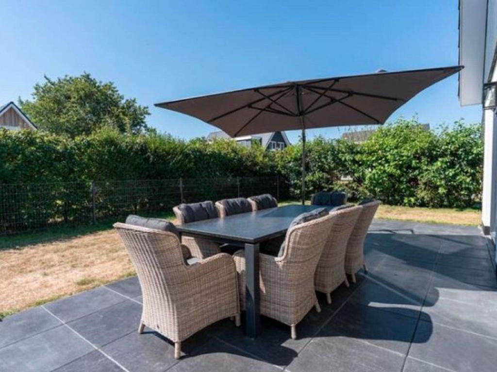 Westermient的住宿－Pleasing Holiday Home in De Koog Texel with Fenced Garden，庭院里配有桌椅和遮阳伞